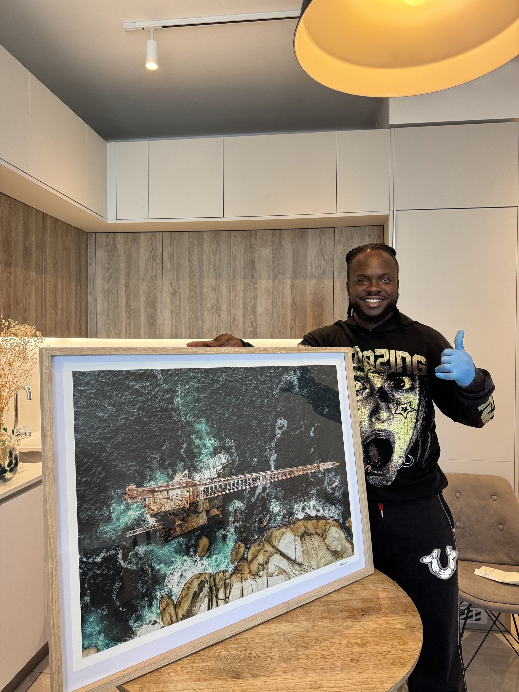 Kingsley, artist and founder of Non Stop Views, holding an NSV print